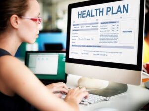 Woman sitting at computer, filling out health plan document